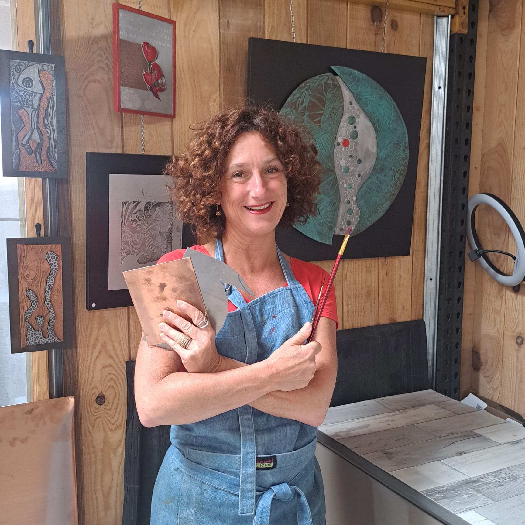 Muriel Carcagno dans son atelier au Pays Basque, artiste graveuse sur métal et émailleuse d'art, présentant une plaque de cuivre et ses créations.