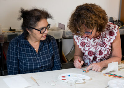 Muriel Carcagno accompagne une participante lors d'un atelier de création de bijoux en émail sur cuivre à Bayonne