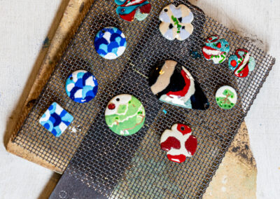 Créations réalisées lors d'un atelier d'émail sur cuivre au Pays Basque : bijoux et médaillons émaillés fabriqués à la main par les participants.