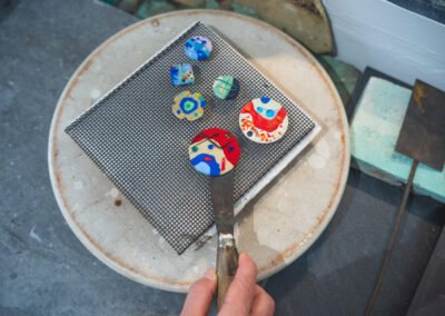 Médaillons en émail sur cuivre posés sur une grille pour séchage avant cuisson à Bayonne